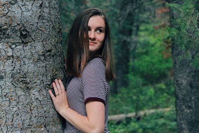 Beautiful young woman standing on tree trunk