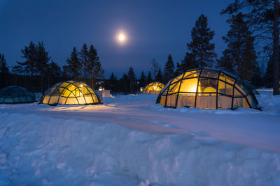 Snow covered land against sky at night during winter