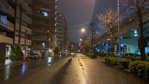 Empty road amidst buildings at night