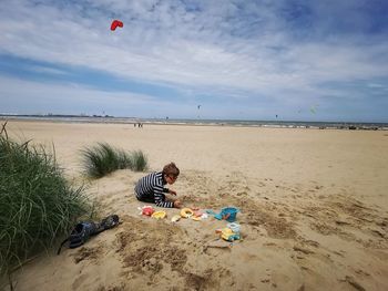 Boy playing with toy on beach against sky