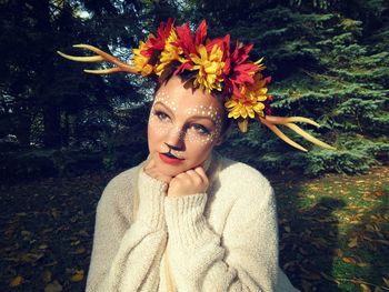 Young woman with face paint and headdress against trees
