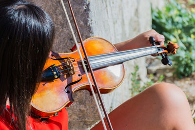 Close-up of woman playing violin while sitting outdoors