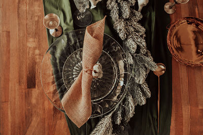 Christmas table setting, scourge napkin on a glass plate, decorated with cotton, gold cutlery