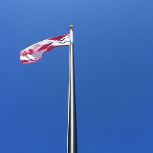 Low angle view of flags against blue sky