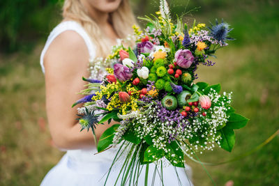 Midsection of woman holding bouquet of flowering plant