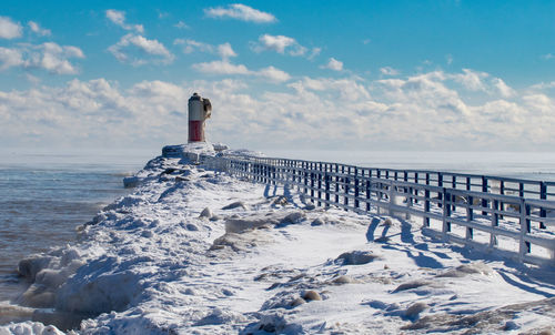 Lighthouse by sea against sky during winter