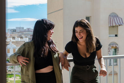 Two young women are having fun on a balcony of her house