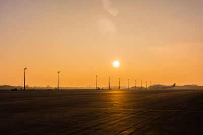 Silhouette of factory against sky during sunset