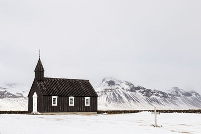 Church on snow covered landscape against clear sky