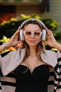 Portrait of a woman's face in sunglasses and wireless headphones walking in the city in autumn