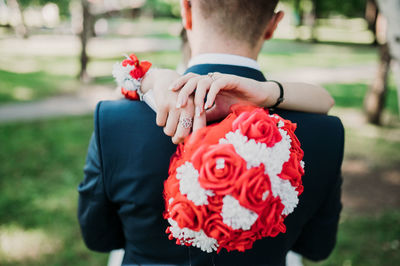 Midsection of man holding red rose