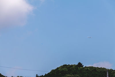 Low angle view of airplane flying against clear blue sky