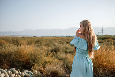 Rear view of woman standing by plants against sky