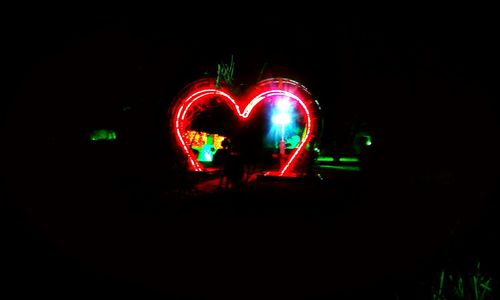 Heart shape illuminated light over black background