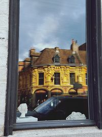 Buildings against sky seen through window