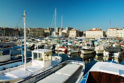 Boats moored at harbor against clear sky