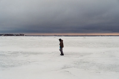 Full length of man standing on beach against sky during sunset