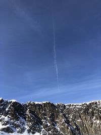 Low angle view of snowcapped mountain against blue sky