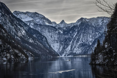 Scenic view of lake by snowcapped mountains against sky