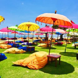 Multi colored umbrellas on grass against sky