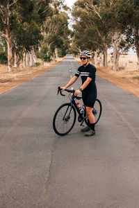 Full length of woman standing with bicycle on road