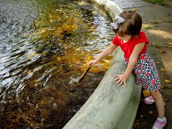 High angle view of cute girl playing near pond in park