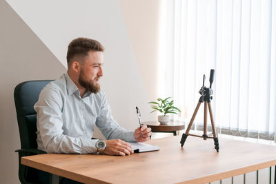 Smiling bearded business man, filming his video blog episode using smartphone