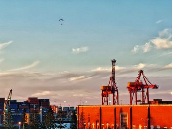 Cranes at harbor against sky in city