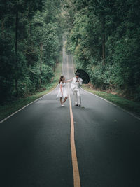 People walking on road along trees