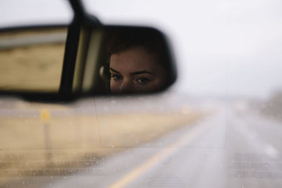 Reflection of woman on rear-view mirror in car