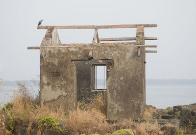 Old building by sea against clear sky