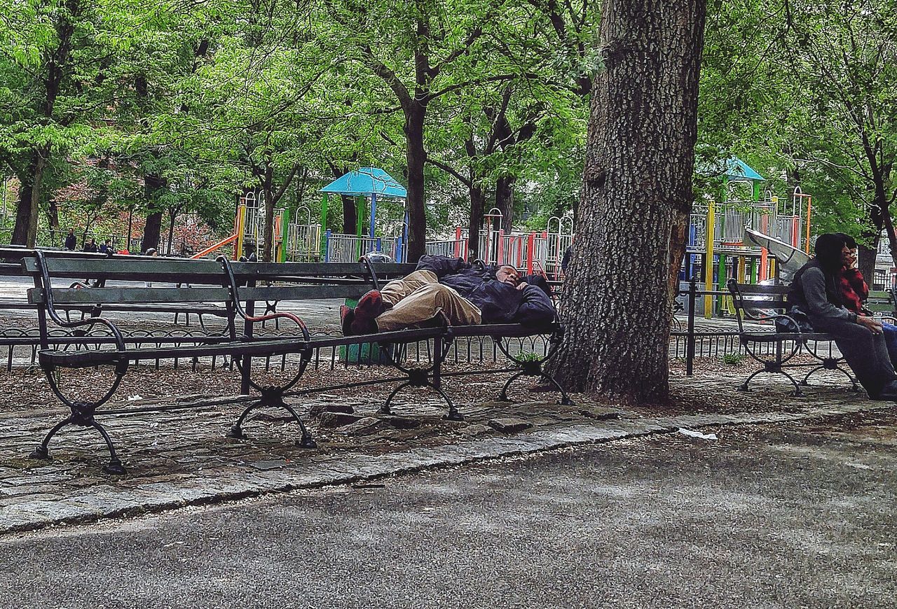 MAN SITTING ON TREE TRUNK