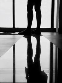 Low section of silhouette person standing by reflection on floor