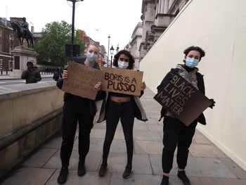 Full length of people holding umbrella on street in city