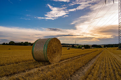 Hay bales on field against sky during sunset