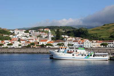 Boats in sea by townscape against sky