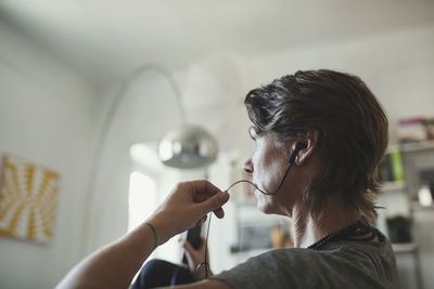 Side view of architect talking through in-ear headphones at home