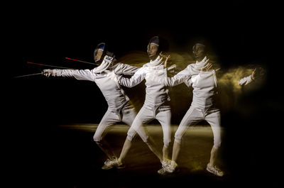 Multiple image of female athlete fencing against black background