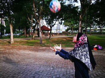Girl playing with ball on footpath in park
