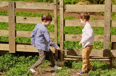 Boy standing by fence in farm