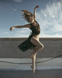 Full length of woman jumping against wall