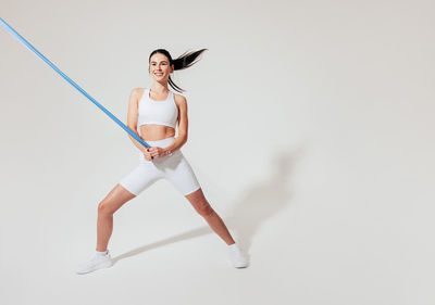 Full length of woman exercising against white background