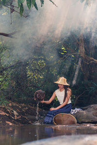 Young woman pouring water from basket at lakeshore