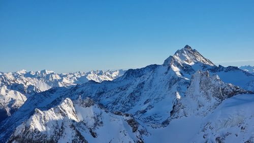 Scenic view of snowcapped mountains against clear blue sky