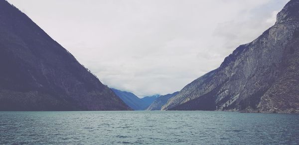 Scenic view of sea by mountains against sky