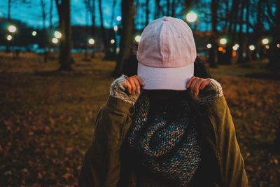 Midsection of woman standing by tree during winter at night