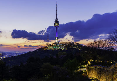 Communications tower and buildings against sky at sunset