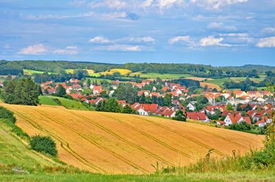 Scenic view of village on green landscape against sky