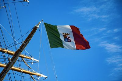 Low angle view of italian flag on tall ship against blue sky