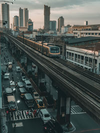 High angle view of train moving on railway bridge against sky in city during sunset